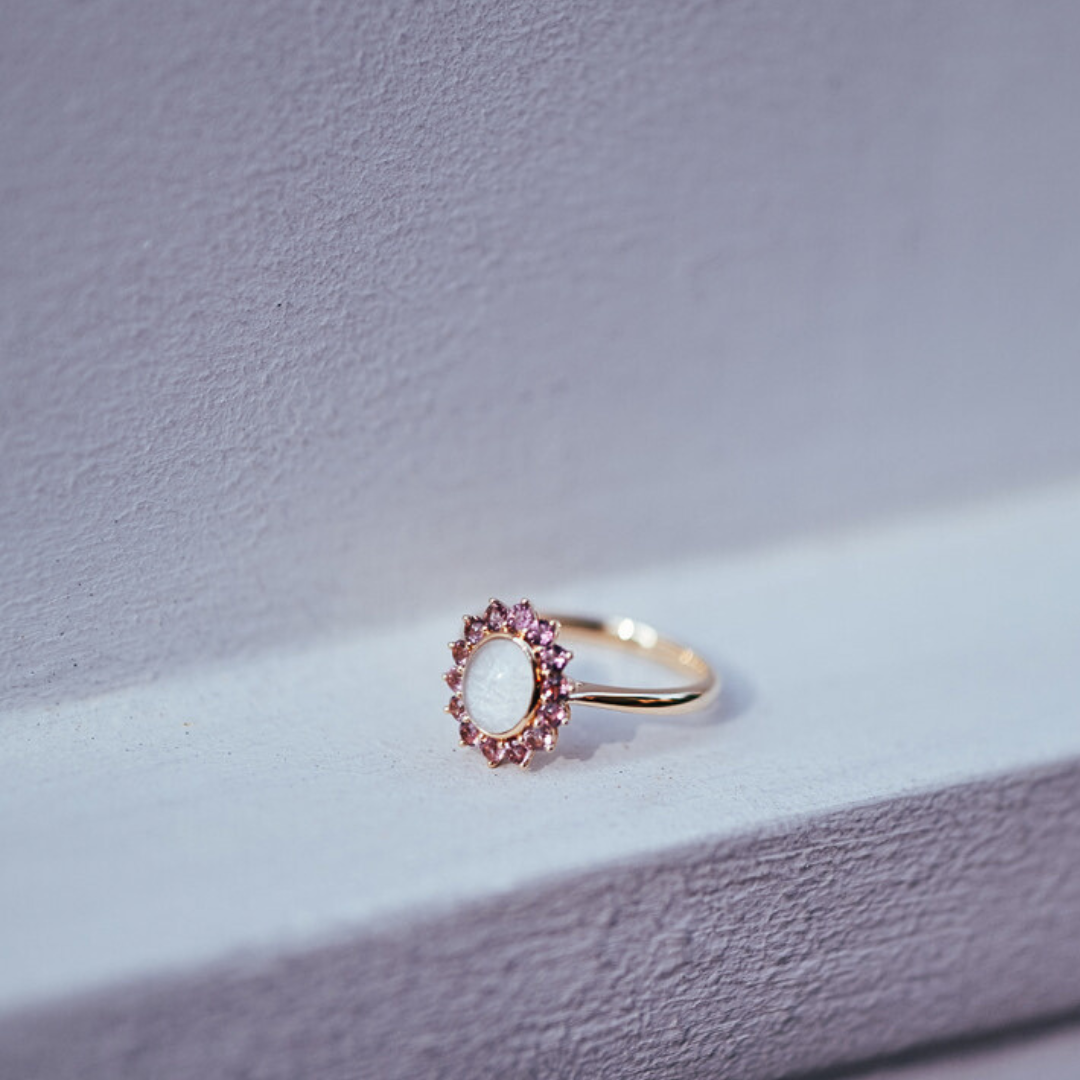 The Roseglow Ring, a breastmilk stone encircled by a halo of pink tourmalines in solid gold