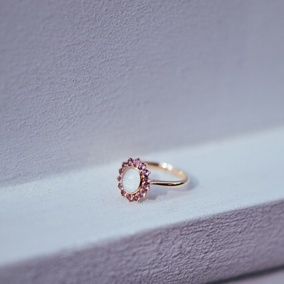 The Roseglow Ring, a breastmilk stone encircled by a halo of pink tourmalines in solid gold