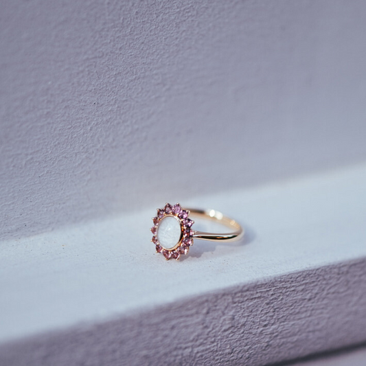 The Roseglow Ring, a breastmilk stone encircled by a halo of pink tourmalines in solid gold