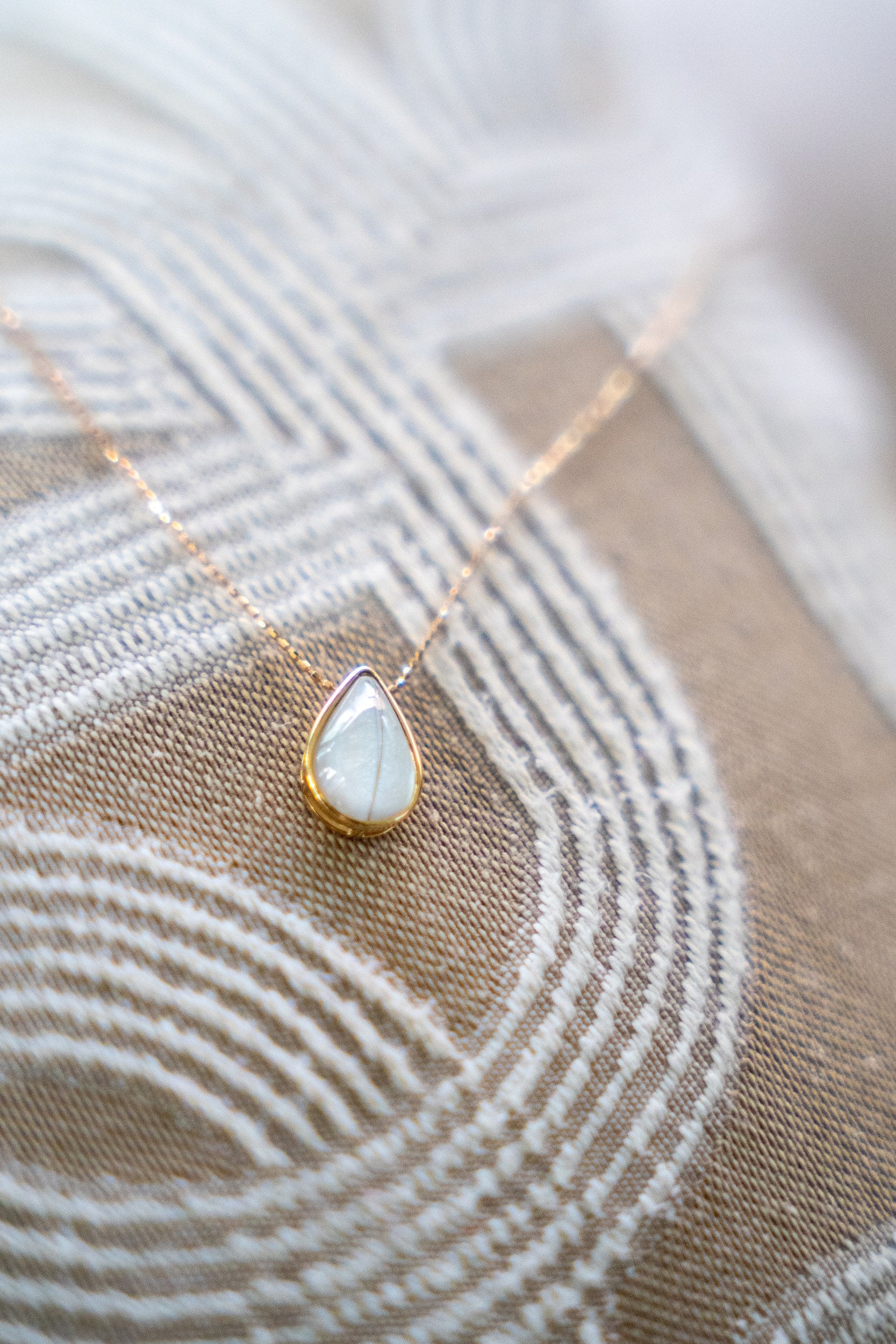 Solid gold breastmilk necklace with a teardrop keepsake stone, the Dewdrop